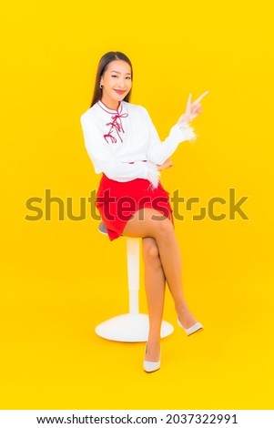 Portrait beautiful young asian woman sit on chair on yellow background