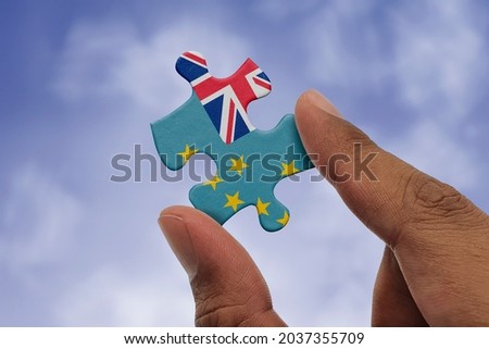Hand holding piece of jigsaw puzzle with flag of Tuvalu. Jigsaw puzzle of Tuvalu flag on sky background.