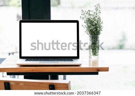 Blank screen laptop computer and flower on wooden table with copy space.
