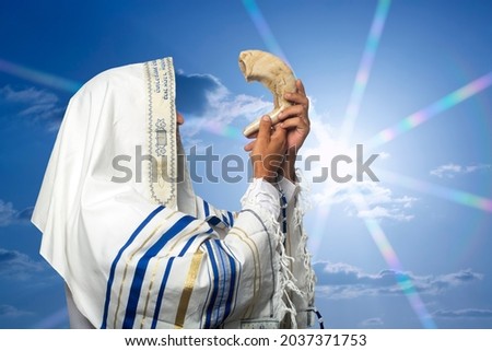 Jewish man Rabbi in tallit blowing the Shofar of Rosh Hashanah (New Year) on sunset time. Blowing the shofar for the Feast of Trumpets, jew in traditional tallith prayer shawl blowing the ram's horn Royalty-Free Stock Photo #2037371753