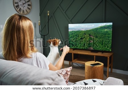 Woman resting at home. Person watch TV set on the sofa and switch channels with remote control Royalty-Free Stock Photo #2037386897