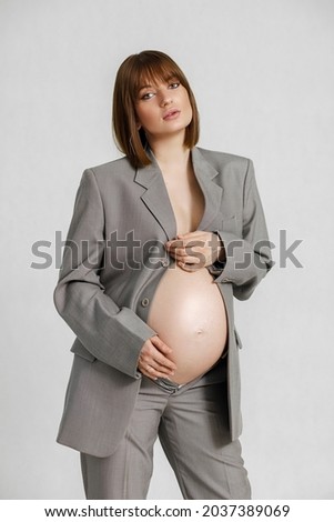 beautiful young pregnant woman with short hair in grey suit