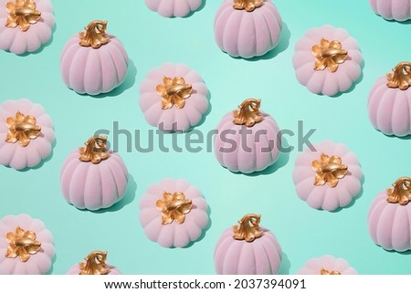 Arranged pink halloween fairy tale pumpkin on mint color background. Minimal concept and pattern.