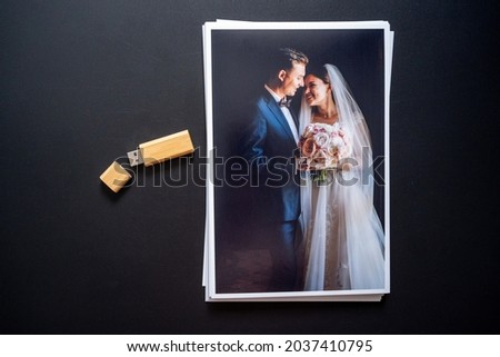 stack of a printed copy of the wedding photos and flash drive. the result of the photographer's work at the wedding. printed products. a photo session of the bride and groom.