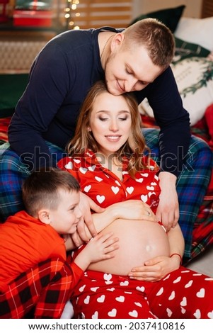 beautiful happy family in pajamas in the New Year's bedroom. traditional winter holidays. festive decor. long-awaited pregnancy.