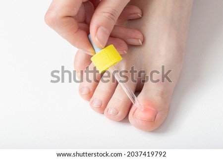 Girl applies nail oil to her toe to strengthen and improve the growth of the nail and cuticle. Copy space for text Royalty-Free Stock Photo #2037419792
