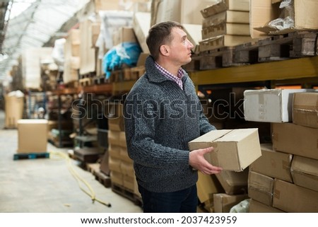 Male seller holding box in warehouse. High quality photo