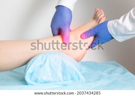 The doctor examines the patient's sore ankle joint for fractures. Ankle disease concept, sprain, gout. Pathology Royalty-Free Stock Photo #2037434285