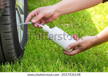 A man pours a car emergency sealant to puncture the wheels. Repairing a puncture of a wheel on the road Royalty-Free Stock Photo #2037436148
