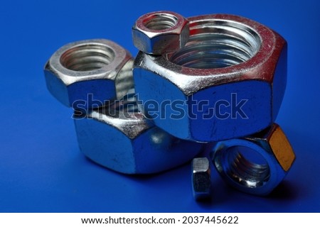 chrome plated, metal nuts of different sizes, highlighted in different colors, laid out on a blue background.