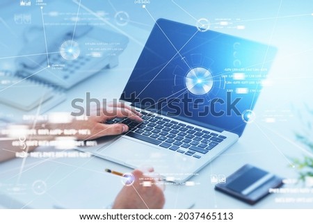 Businessman is working on laptop and taking notes in notebook. Office workplace with phone and desk in the background. Digital interface with circle hologram connected with line in foreground
