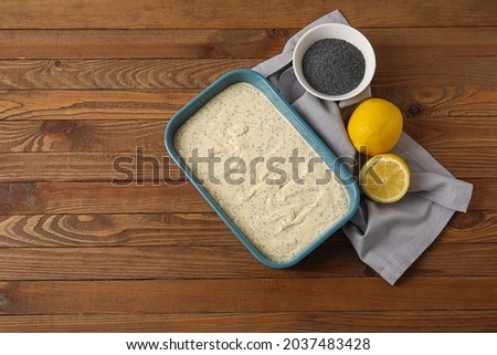 Baking tin with uncooked poppy seed cake on wooden table