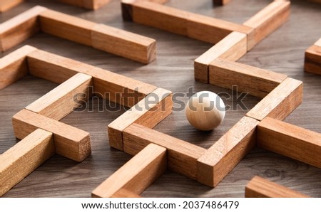Wooden ball in a maze and thinking the best way to go. Royalty-Free Stock Photo #2037486479