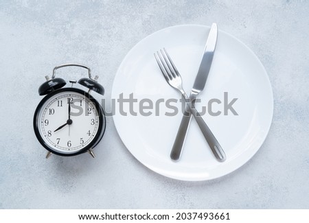 Intermitted farsting diet concept - empty plate with fork and knife and timer Royalty-Free Stock Photo #2037493661