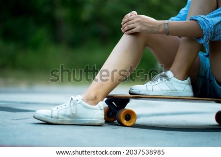 Teenage girl in a blue sport clothing is siting on a longboard. May be a concept of a teenage sports, teenagers