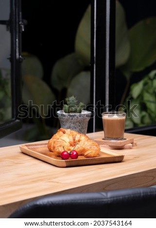 Fresh butter croissants and hot coffee latte in a wooden table, near open windows. selective focus. 