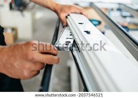 Young male worker assembling products in modern PVC and aluminum doors and windows production factory. Extreme close up shot of worker's hands. Royalty-Free Stock Photo #2037546521