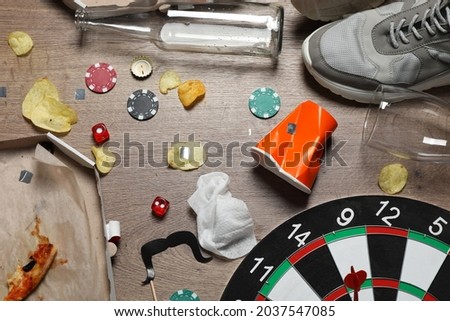 Food leftovers, shoes and elements of different games after party on wooden floor, flat lay Royalty-Free Stock Photo #2037547085