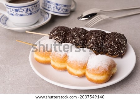 Doughnut satay or donat sate  with chocolate sprinkles and doughnut satay with a sprinkling of powdered sugar, along with a cup of coffee with a cup with a picture of vines