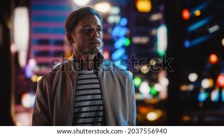 Handsome Blonde Man Standing on a Street of a Night City. Thoughtful Attractive Young Man Traveling, Looking Around Urban Center Contemplating Business Ideas, Future Career. Air of New Possibilities Royalty-Free Stock Photo #2037556940