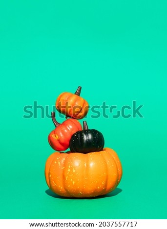 Retro styled conceptual still life arrangement with pumpkins on green background. Halloween holiday theme creative concept. Autumn colors. Modern aesthetic. Copy space.