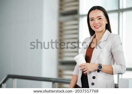 Portrait Of A middle-aged Asian woman Successful Business Woman Holding White take away coffee Of Hot Drink In Hand at office