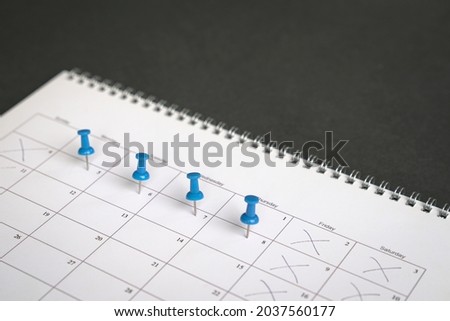 Blue pins on four days in a week on a calendar. Friday, Saturday and Sunday crossed out. Four day work week concept. Royalty-Free Stock Photo #2037560177