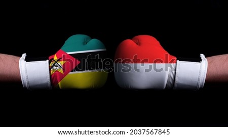 Two hands of wearing boxing gloves with Indonesia and Mozambique flag. Boxing competition concept. Confrontation between two countries