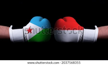 Two hands of wearing boxing gloves with Indonesia and Djibouti flag. Boxing competition concept. Confrontation between two countries