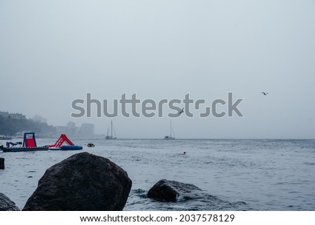 An empty beach with Inflatable floating water slide on a rainy day in the autumn