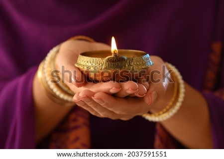 Woman holding lit diya lamp in hands, closeup. Diwali celebration Royalty-Free Stock Photo #2037591551