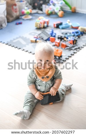 adorable cute baby boy playing with parents cell phone on the floor. happy childhood.
