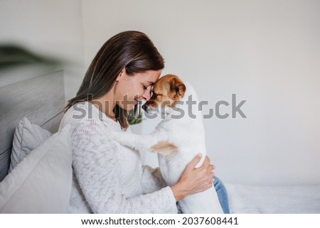happy caucasian woman at home cuddling on bed with cute jack russell dog. Foreheads together. Pets, love and relax at home Royalty-Free Stock Photo #2037608441