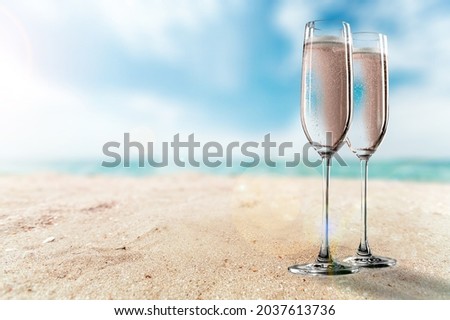 Two glasses of cold rose wine on sandy beach in sunny day,