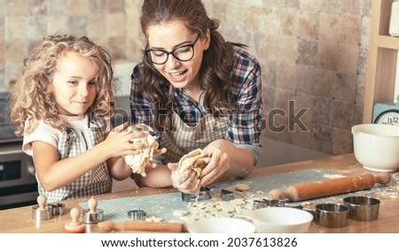 	
Mother and daughter playing in the kitchen and preparing dough to make cookies.Family concept.	
