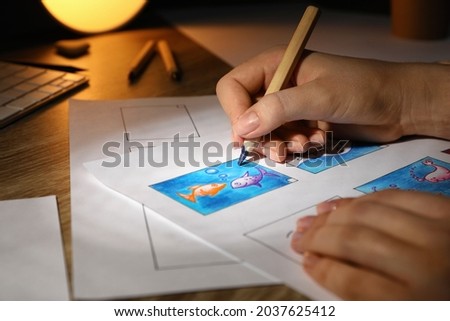 Woman drawing cartoon sketch in storyboard at workplace, closeup. Pre-production process