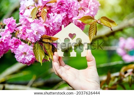 The girl holds the house symbol against the background of blossoming Sakura
