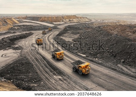 Large quarry dump truck. Big yellow mining truck at work site. Loading coal into body truck. Production useful minerals. Mining truck mining machinery to transport coal from open-pit production Royalty-Free Stock Photo #2037648626