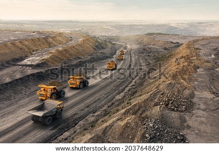 Large quarry dump truck. Big yellow mining truck at work site. Loading coal into body truck. Production useful minerals. Mining truck mining machinery to transport coal from open-pit production Royalty-Free Stock Photo #2037648629