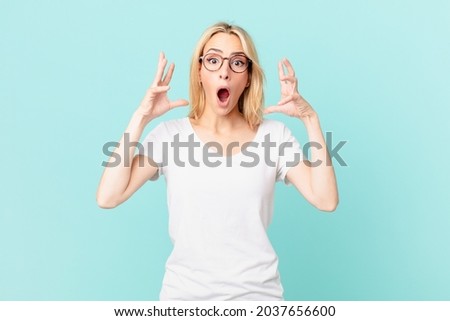 young blonde woman screaming with hands up in the air