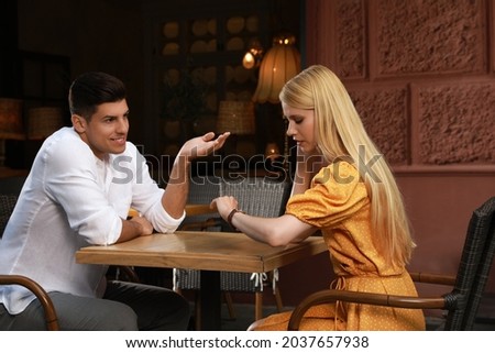 Young woman checking time during boring date in outdoor cafe Royalty-Free Stock Photo #2037657938