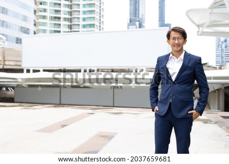 Portrait asian businessman wearing suit jacket standing outdoor in the city. Empty banner for text background.