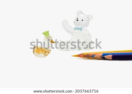 A bear and a goose next to some colored pencils