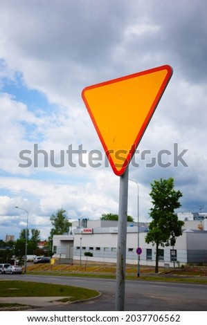 A vertical shot of a yellow traffic sign by a street