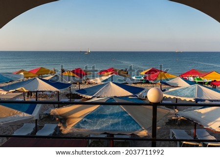 View from a wooden arch to the beach with colorful beach umbrellas on a summer day on the Black Sea coast.  Iron Port (Zaliznyi Port), Kherson Oblast, Ukraine.