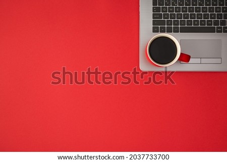 Overhead photo of laptop with cup of coffee isolated on the red backdrop with copyspace