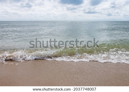 Black sea on a sunny day with clouds in the sky. Waves with white foam and sandy shore