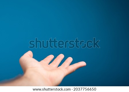 A man's open palm isolated on a blue background with space for text