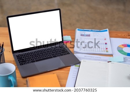 Image on a desk with document and a laptop blank white screen placed at the office.