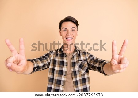 Photo of young cute guy v-sign wear checkered shirt isolated on beige color background
